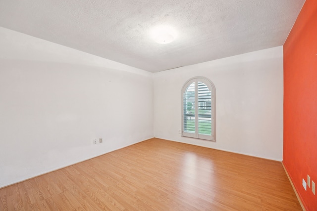 spare room with a textured ceiling and wood finished floors