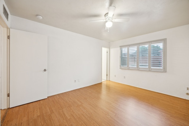 unfurnished room with visible vents, a ceiling fan, and wood finished floors