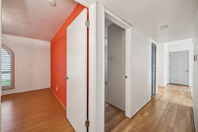 hallway with a textured ceiling and light wood finished floors