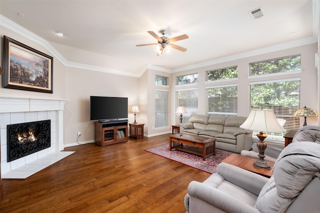 living room featuring ceiling fan, visible vents, crown molding, wood finished floors, and baseboards