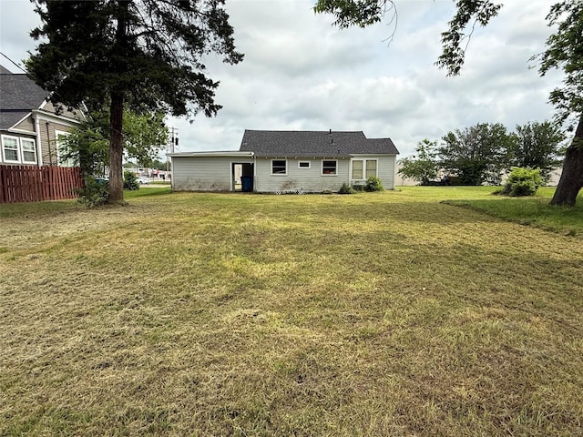 rear view of house with fence and a yard