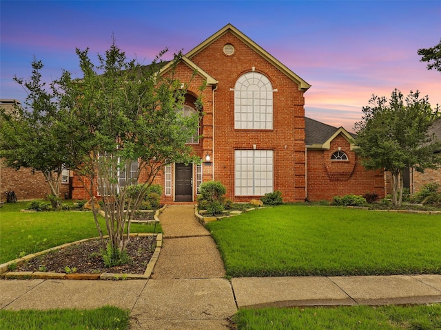 traditional-style house with brick siding and a front lawn