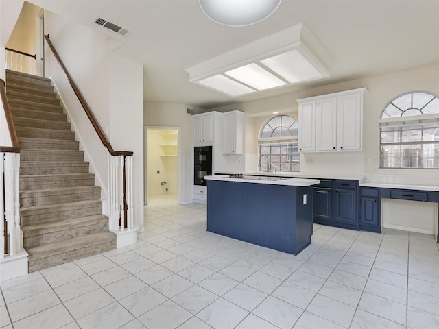 1524 Santa Fe Trl, Carrollton, TX 75007 - kitchen featuring visible vents, a kitchen island, light countertops, white cabinets, and blue cabinets