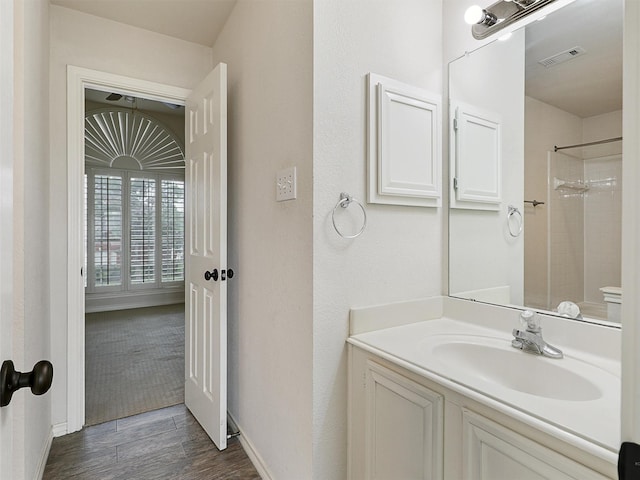 full bathroom featuring vanity, baseboards, wood finished floors, a shower, and visible vents