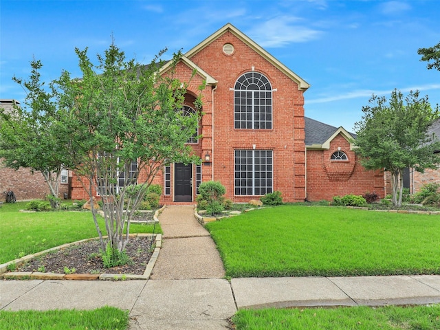 traditional-style home featuring brick siding and a front yard