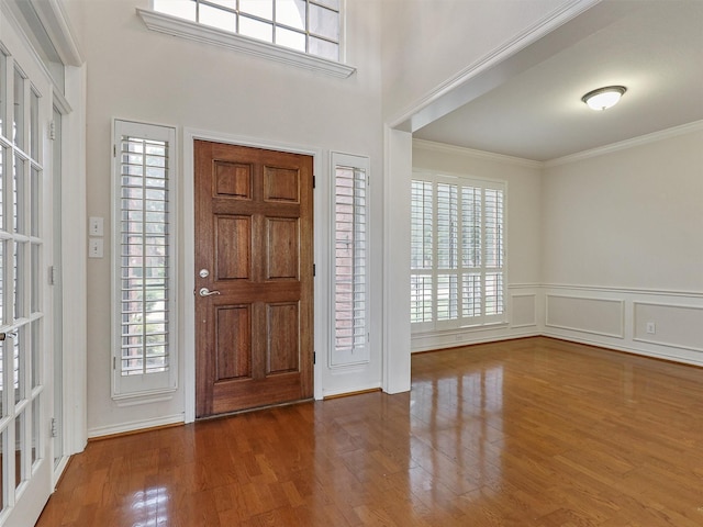 foyer featuring crown molding, plenty of natural light, and wood finished floors