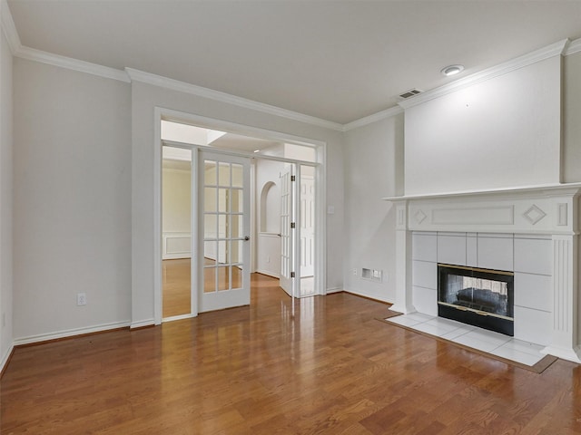 unfurnished living room with french doors, baseboards, wood finished floors, visible vents, and ornamental molding