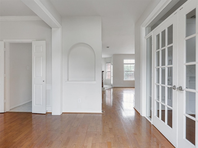 interior space with baseboards, ornamental molding, french doors, and wood finished floors