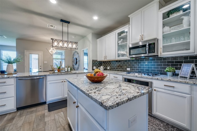 kitchen with visible vents, decorative backsplash, white cabinets, a sink, and stainless steel appliances