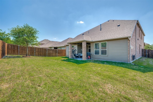 rear view of property with brick siding, a fenced backyard, a patio area, and a yard