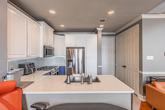 kitchen featuring appliances with stainless steel finishes, a peninsula, white cabinetry, visible vents, and ornamental molding