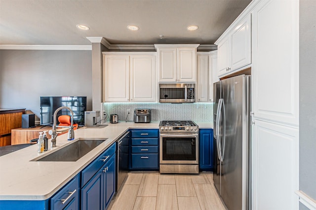 kitchen with blue cabinetry, appliances with stainless steel finishes, a sink, a peninsula, and white cabinetry