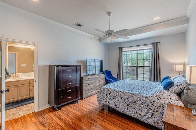 bedroom featuring visible vents, crown molding, light wood-type flooring, a sink, and ensuite bath