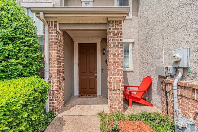 doorway to property with brick siding and stucco siding