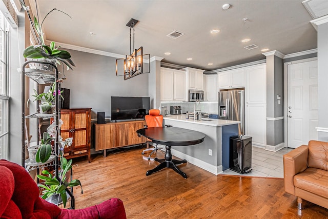 kitchen with appliances with stainless steel finishes, light wood-style flooring, open floor plan, visible vents, and ornamental molding
