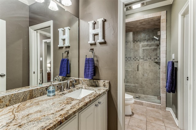 bathroom with tile patterned flooring, a stall shower, vanity, baseboards, and toilet