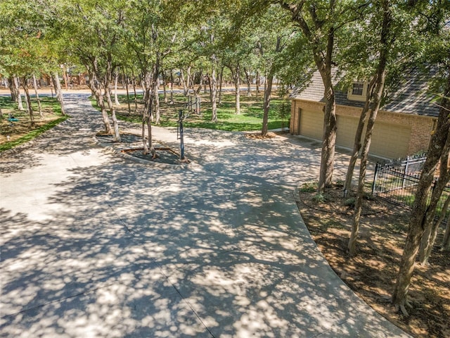 view of home's community featuring a garage, fence, and concrete driveway