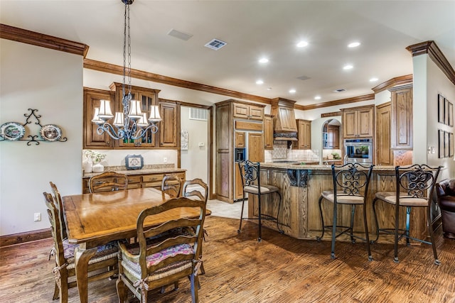 dining space featuring visible vents, ornamental molding, wood finished floors, and a chandelier