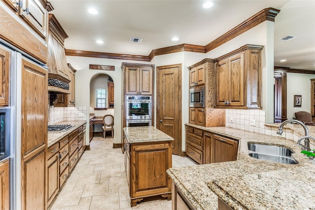kitchen with a sink, arched walkways, stainless steel appliances, visible vents, and ornamental molding