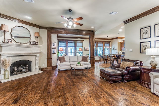 living area featuring crown molding, visible vents, wood finished floors, ceiling fan, and a fireplace with raised hearth