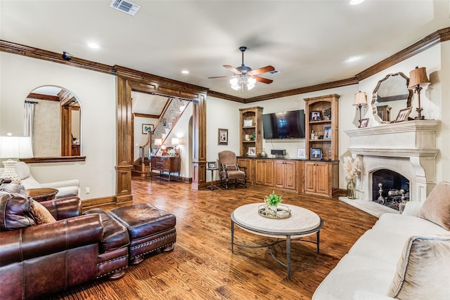 living area featuring ceiling fan, baseboards, wood finished floors, visible vents, and ornamental molding