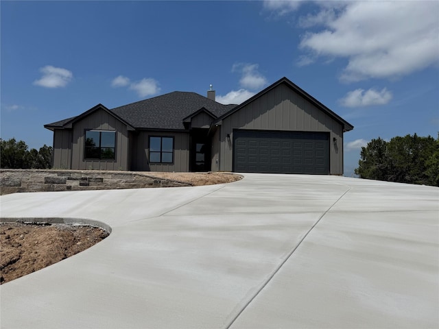 view of front of house with board and batten siding, driveway, a chimney, and a garage