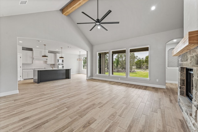 285 Lake Ridge Ct, Bluff Dale, TX 76433 - unfurnished living room featuring ceiling fan, beam ceiling, a stone fireplace, light wood-style floors, and high vaulted ceiling