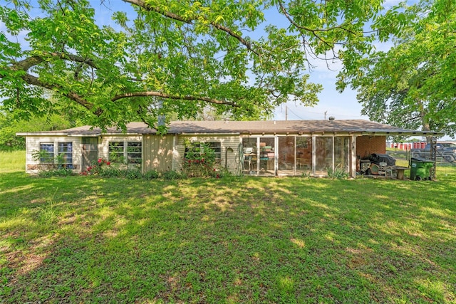 back of house featuring a lawn and a sunroom