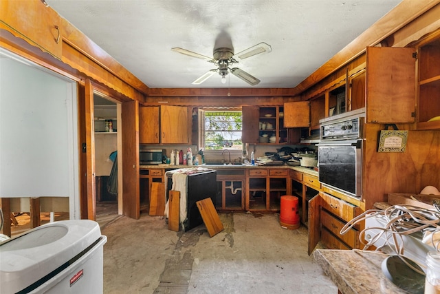 kitchen featuring unfinished concrete floors, open shelves, brown cabinets, a sink, and stainless steel appliances