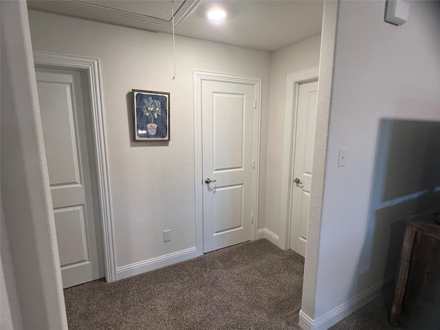 corridor with baseboards, carpet, and attic access