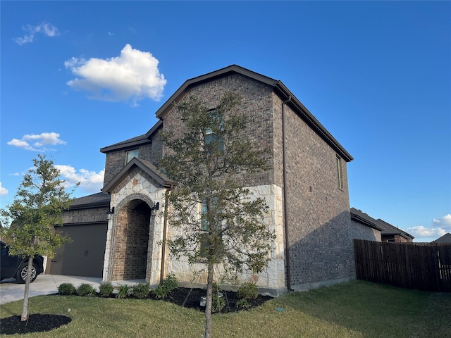 french country home featuring fence, an attached garage, a front lawn, stone siding, and concrete driveway