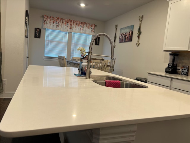 kitchen featuring white cabinets, a sink, a kitchen island with sink, light countertops, and recessed lighting