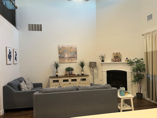 living area featuring visible vents, dark wood-type flooring, a high ceiling, and a fireplace