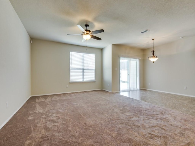 carpeted spare room featuring baseboards, ceiling fan, and visible vents