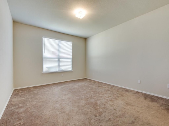 empty room featuring baseboards and carpet flooring