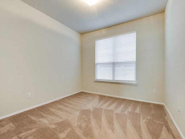 carpeted empty room featuring baseboards