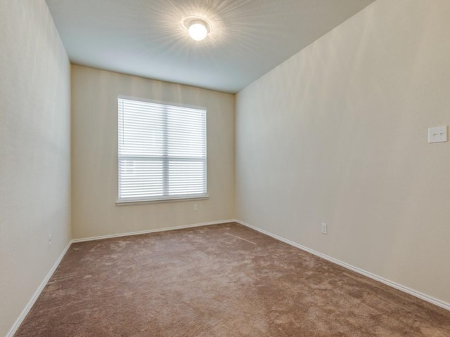 unfurnished room featuring carpet floors and baseboards