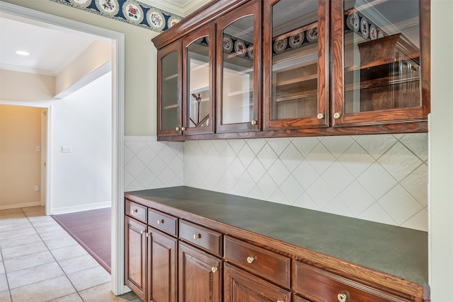 bar featuring light tile patterned floors, decorative backsplash, ornamental molding, and baseboards