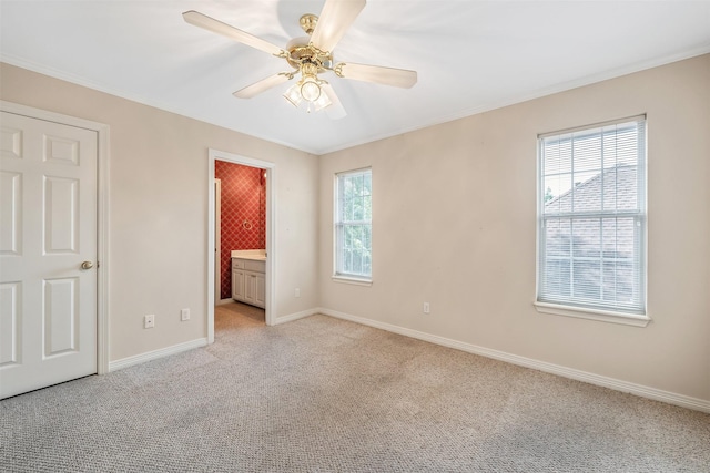 unfurnished bedroom with crown molding, ceiling fan, light colored carpet, ensuite bath, and baseboards