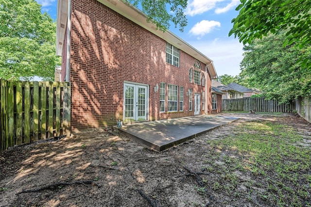 rear view of house featuring a fenced backyard, a patio area, french doors, and brick siding