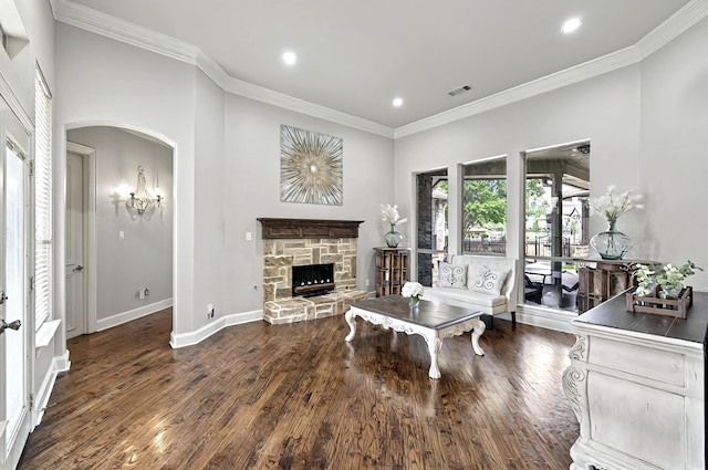 living room with visible vents, ornamental molding, wood finished floors, baseboards, and a stone fireplace