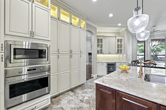 kitchen with crown molding, a sink, appliances with stainless steel finishes, and beverage cooler