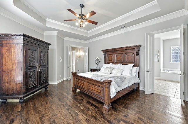 bedroom featuring baseboards, visible vents, wood finished floors, and a raised ceiling