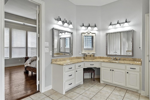 ensuite bathroom with baseboards, tile patterned flooring, vanity, and ensuite bath