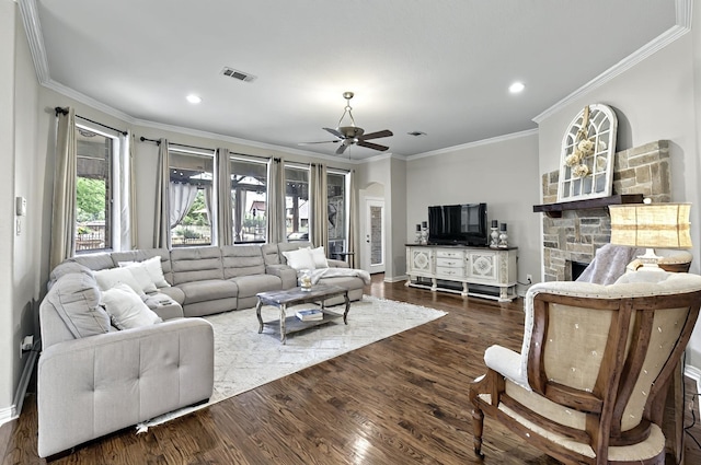 living area with visible vents, ornamental molding, a fireplace, dark wood-type flooring, and a ceiling fan