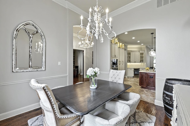 dining space featuring visible vents, arched walkways, a chandelier, wine cooler, and ornamental molding
