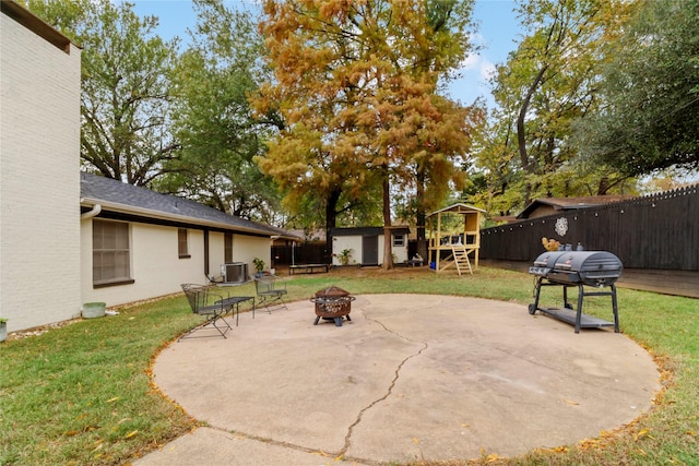 695 SE 32nd St, Paris, TX 75460 - view of patio featuring grilling area, an outdoor structure, a fenced backyard, a storage unit, and a fire pit