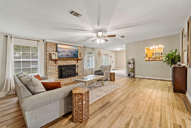 695 SE 32nd St, Paris, TX 75460 - living room with light wood-type flooring, a textured ceiling, a brick fireplace, and ceiling fan