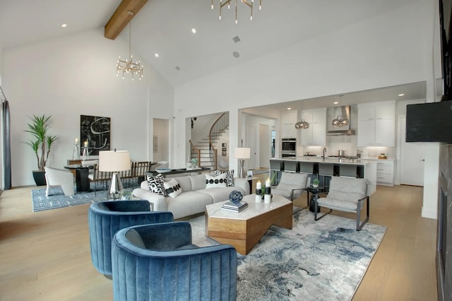 living room with an inviting chandelier, light wood-style floors, high vaulted ceiling, stairs, and beamed ceiling