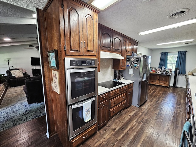 kitchen featuring visible vents, light countertops, a textured ceiling, under cabinet range hood, and stainless steel appliances